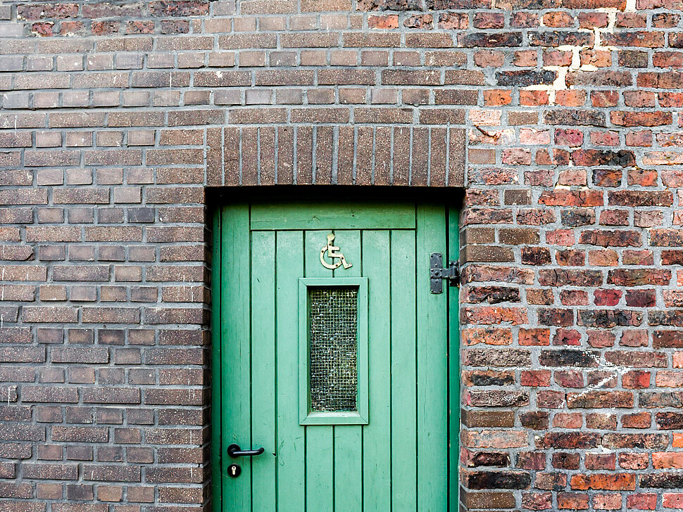 Grüne Eingangstür zum Behinderten-WC am Reiterhof Alsbachtal