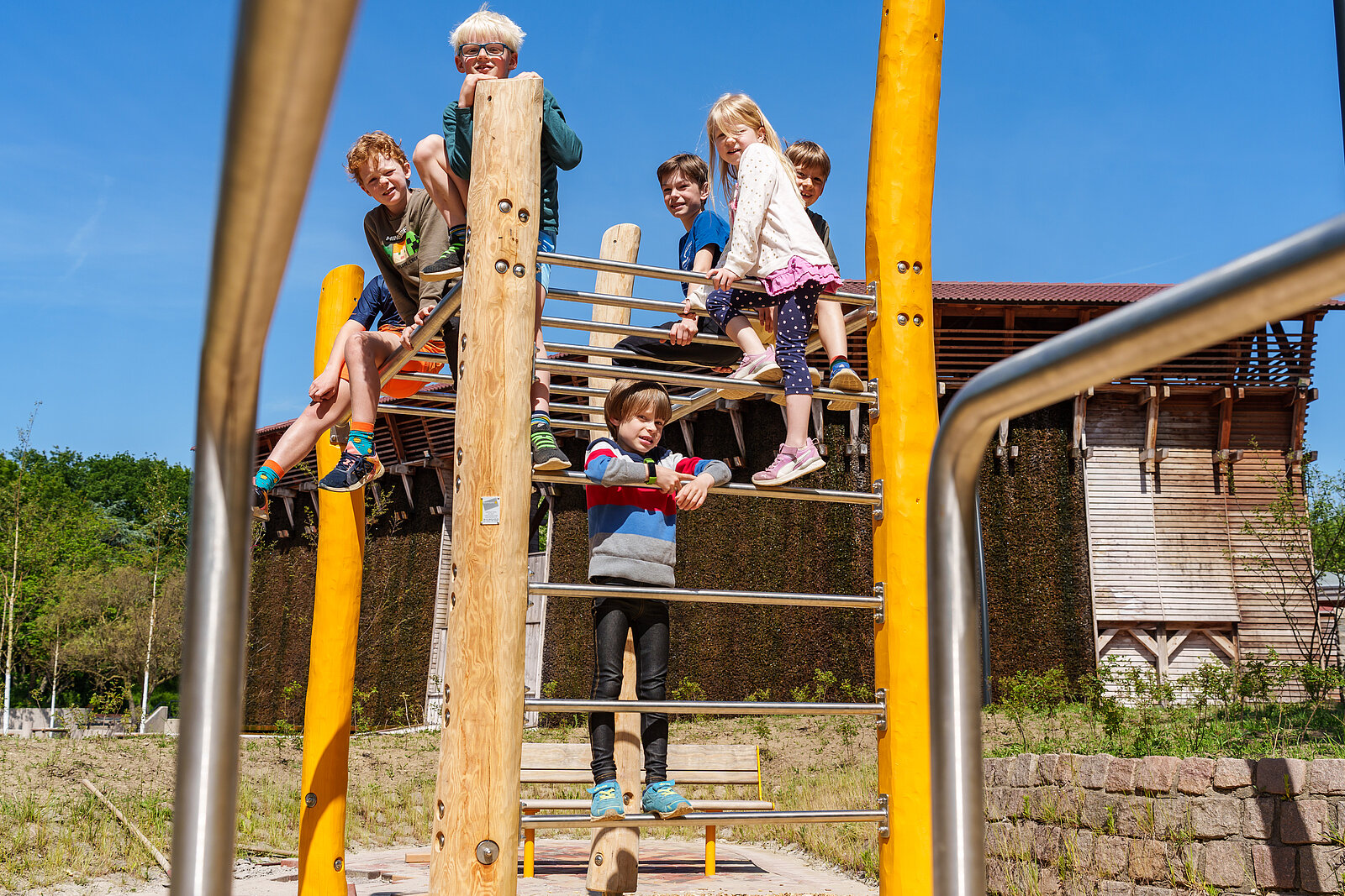 Kinder sitzen auf einem Klettergerüst