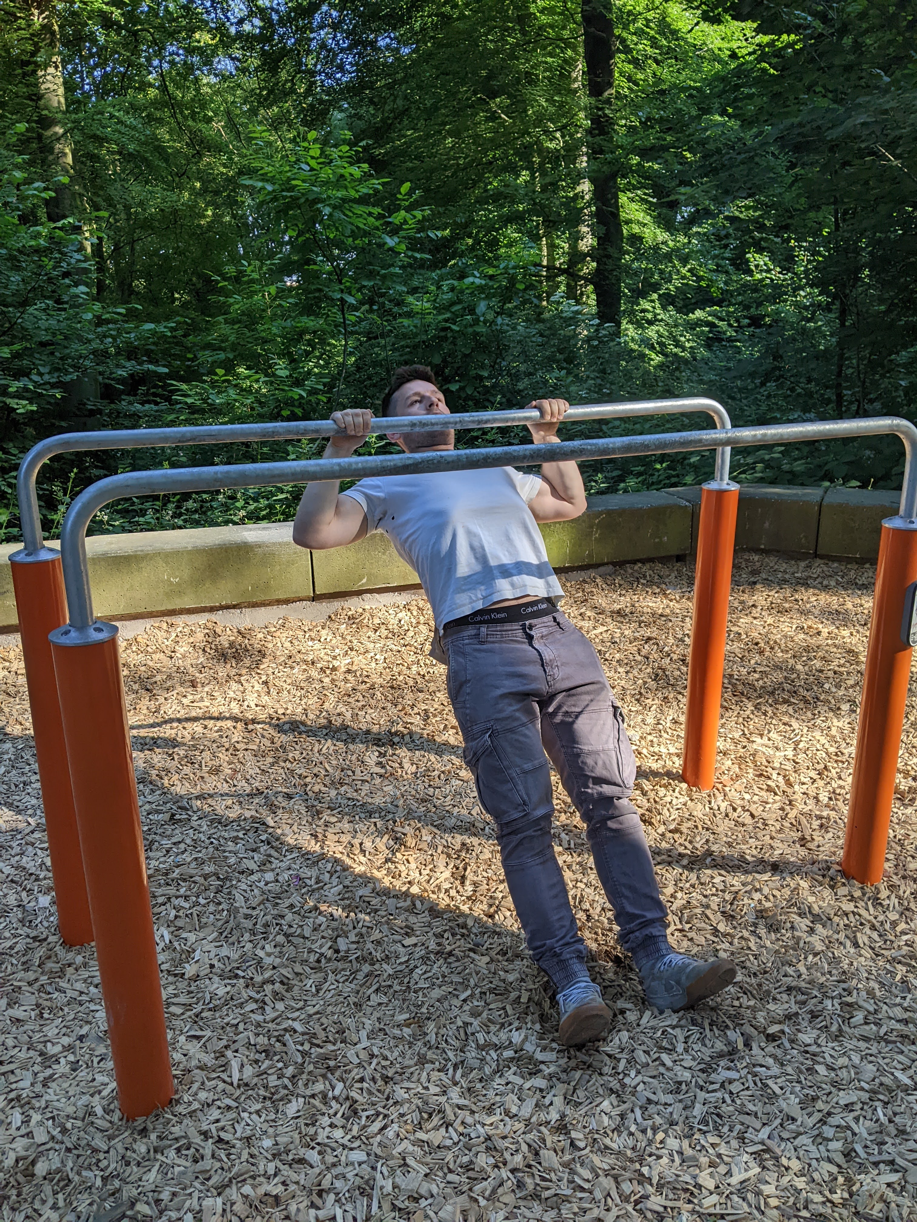 Person bei der Ausführung der geneigten Klimmzüge an einem Barren